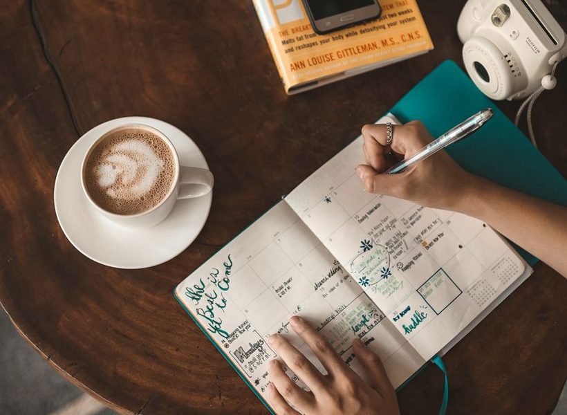 Caderno de planejamento semanal aberto ao lado de uma xicara