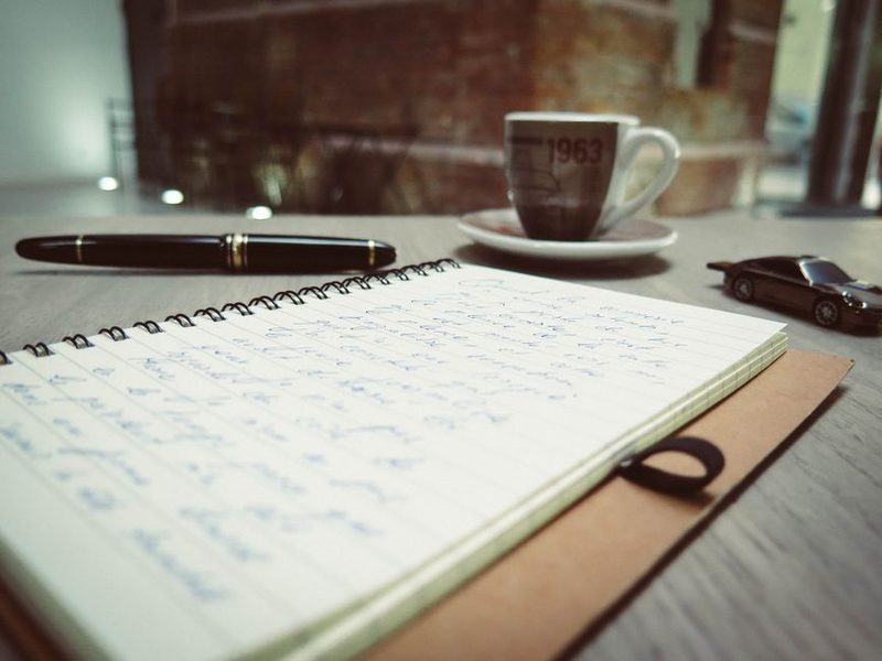 Mesa de trabalho com caderno, caneta e xicara